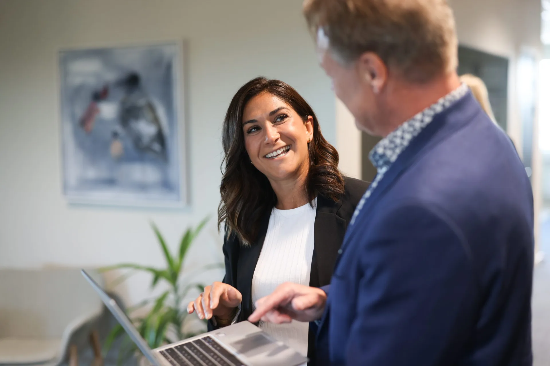 A woman and a colleague discussing work over a laptop in the office.